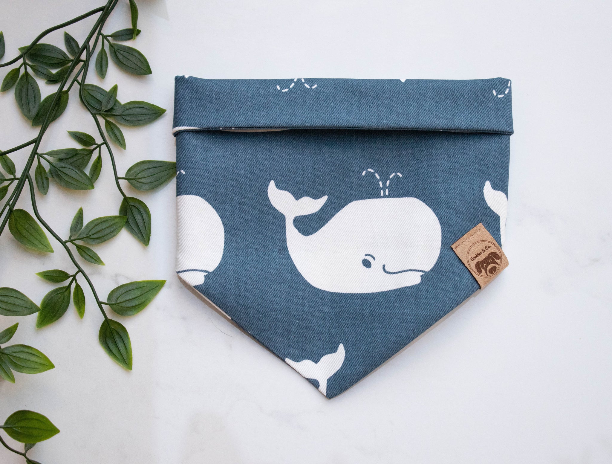 Oh Whale bandana print, featuring large white whales with water spurting out of their blow hole, on a deep dark blue fabric
