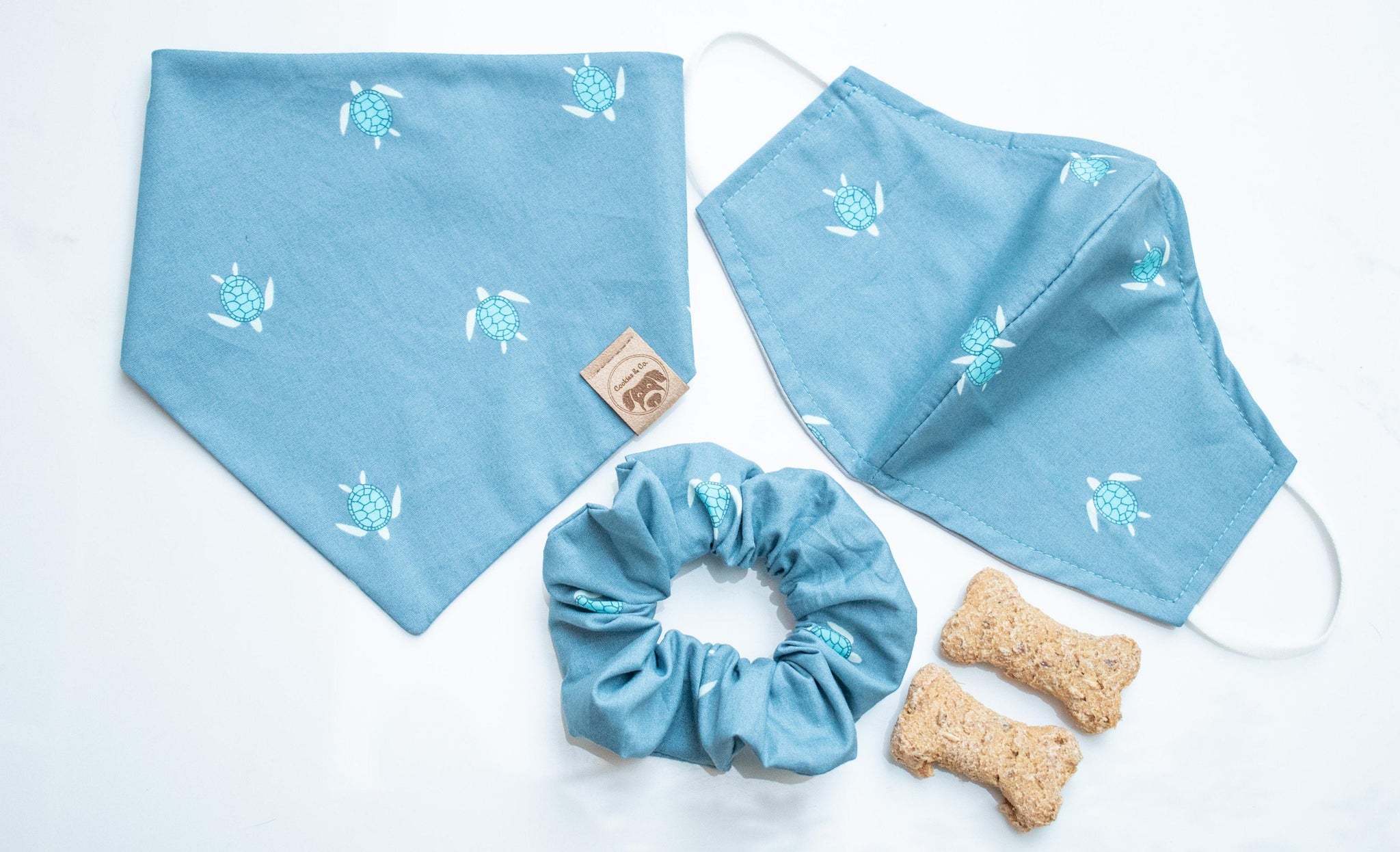 urtle reef bandana print, featuring rows of small, light blue shelled turtles swimming in opposite directions, socially distanced with each other, on a dar blue fabric. Group set, with matching scrunchie and mask