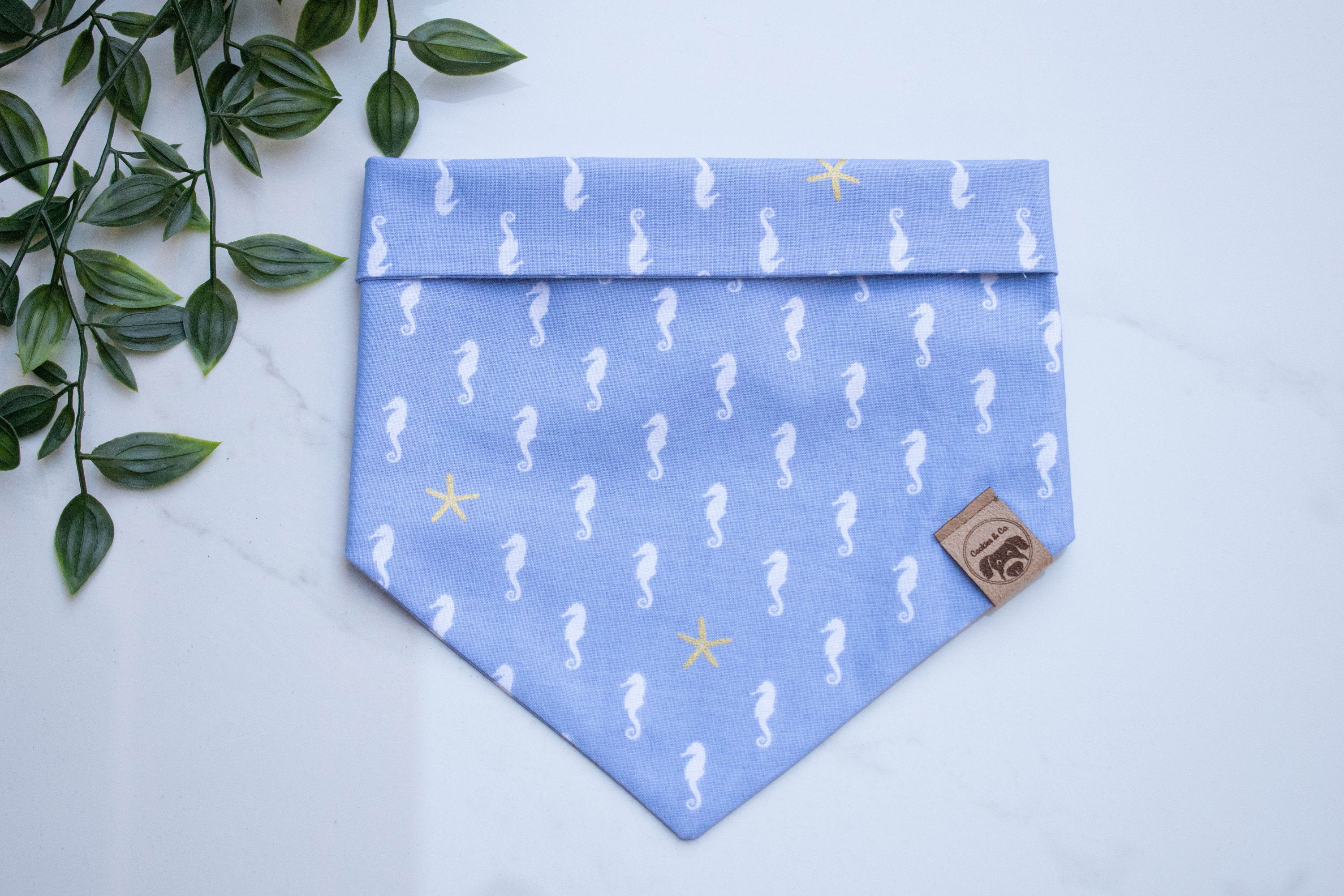 ea Horse bandana print, featuring rows of periwrinkle sea horses oriented facing left, with occasional yellow starfishes, on a light blue background